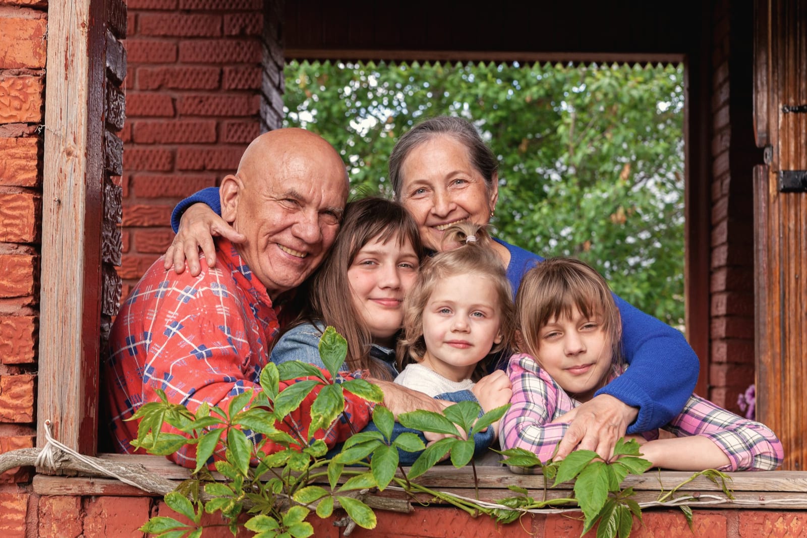 Grandparents and grandchildren smiling at a window